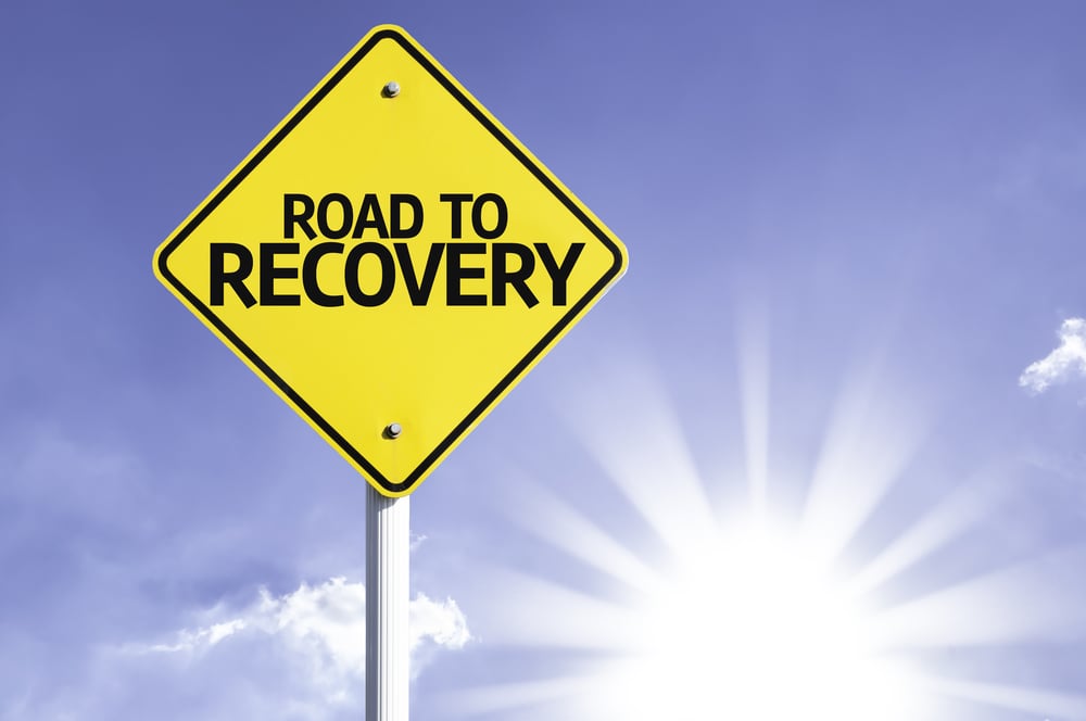 Road To Recovery road sign with sun background